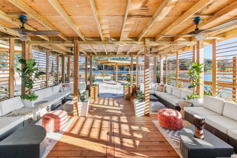 Open-air lakeside pavilion at Fern Oak Estate with timber ceiling, ceiling fans and lounge seating opening onto the water