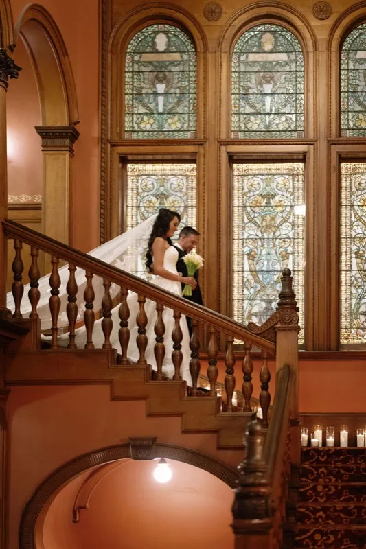 Bride and groom on the staircase under Tiffany stained glass at Flagler College Hotel Ponce de Leon