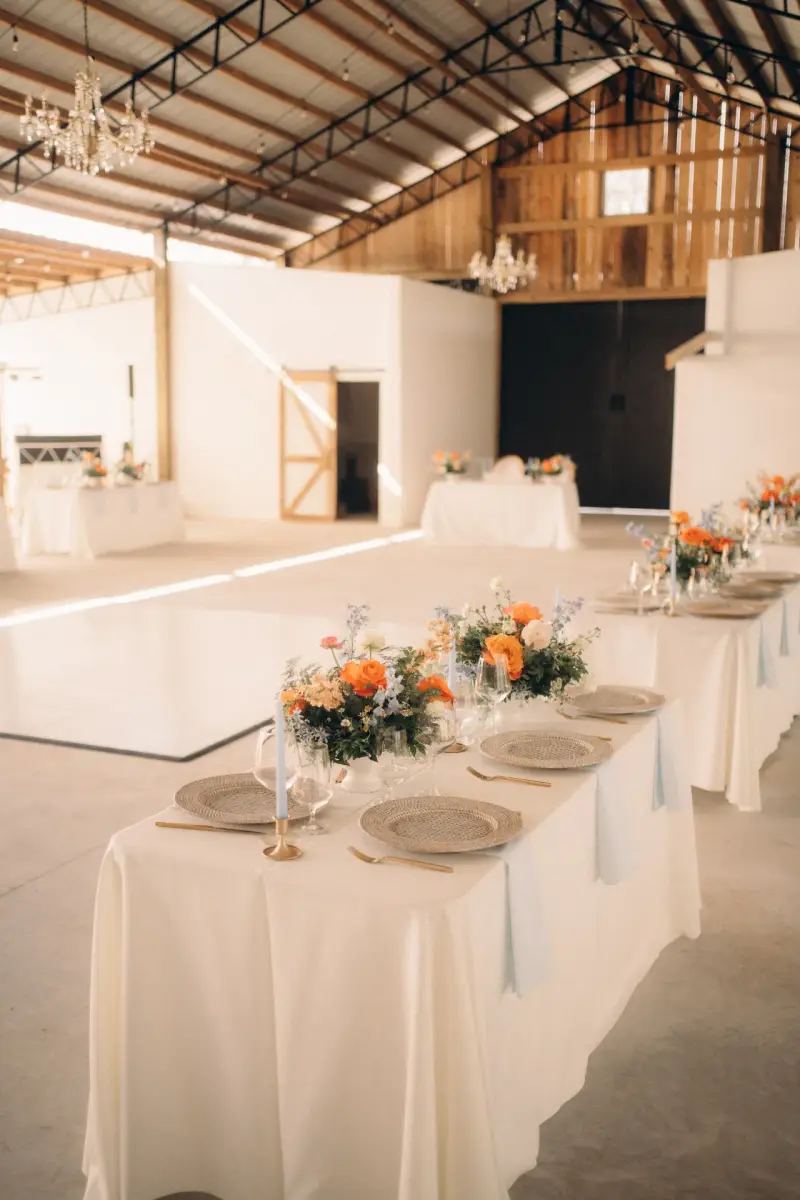 Golden Creek Ranch barn reception with chandeliers, white dance floor and long tables ready for guests