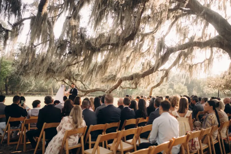 Wedding guests seated under a large Spanish moss oak during a pasture ceremony at Golden Creek Ranch in Palatka Florida