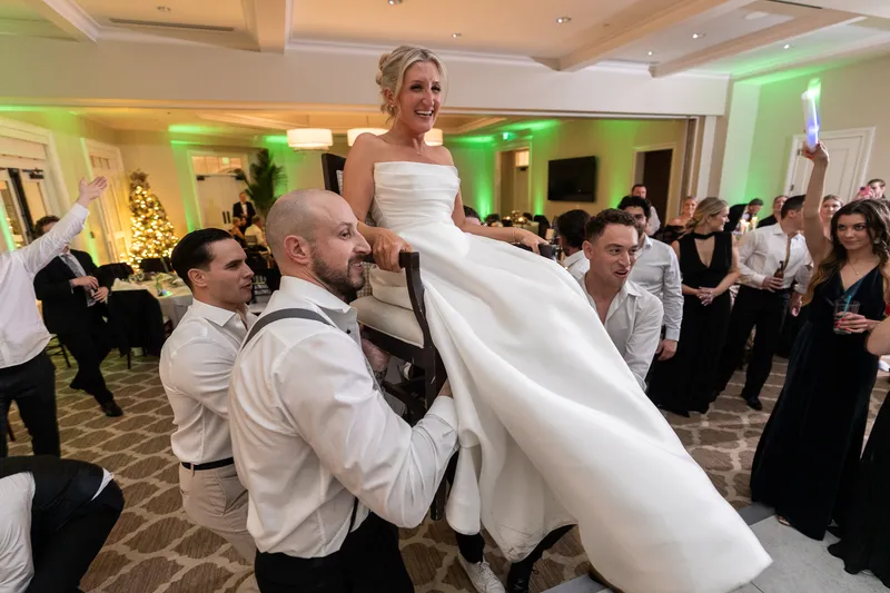 Guests lifting the couple on chairs during the hora at a Sawgrass Country Club wedding