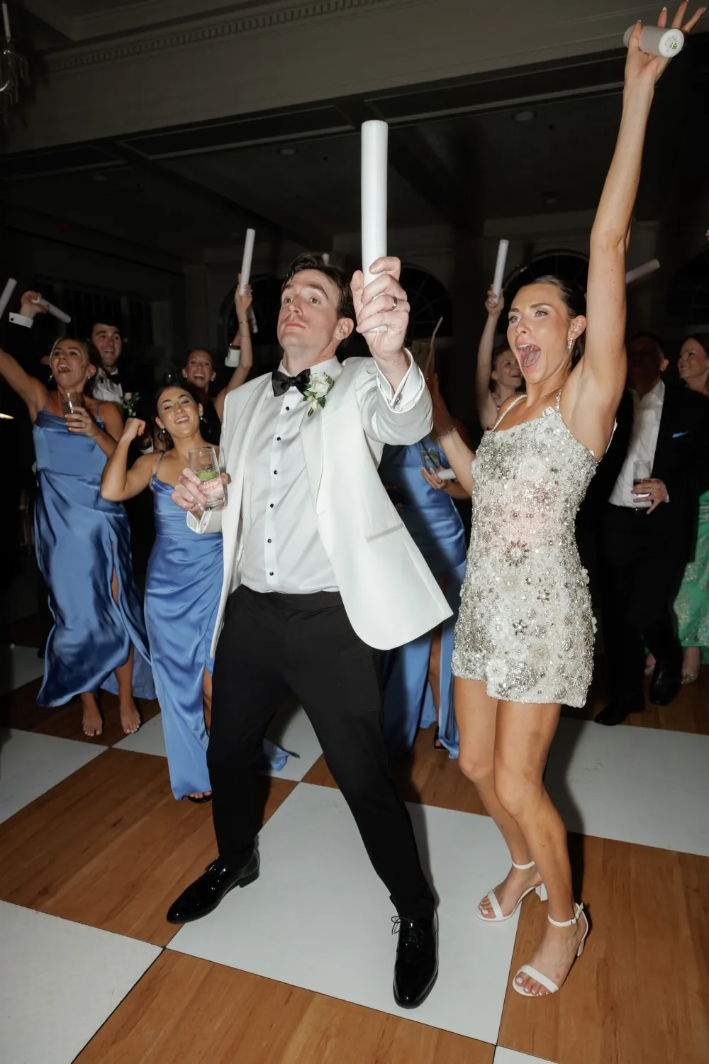 Bride and groom going off on the Timuquana dance floor with the bridal party cheering behind them