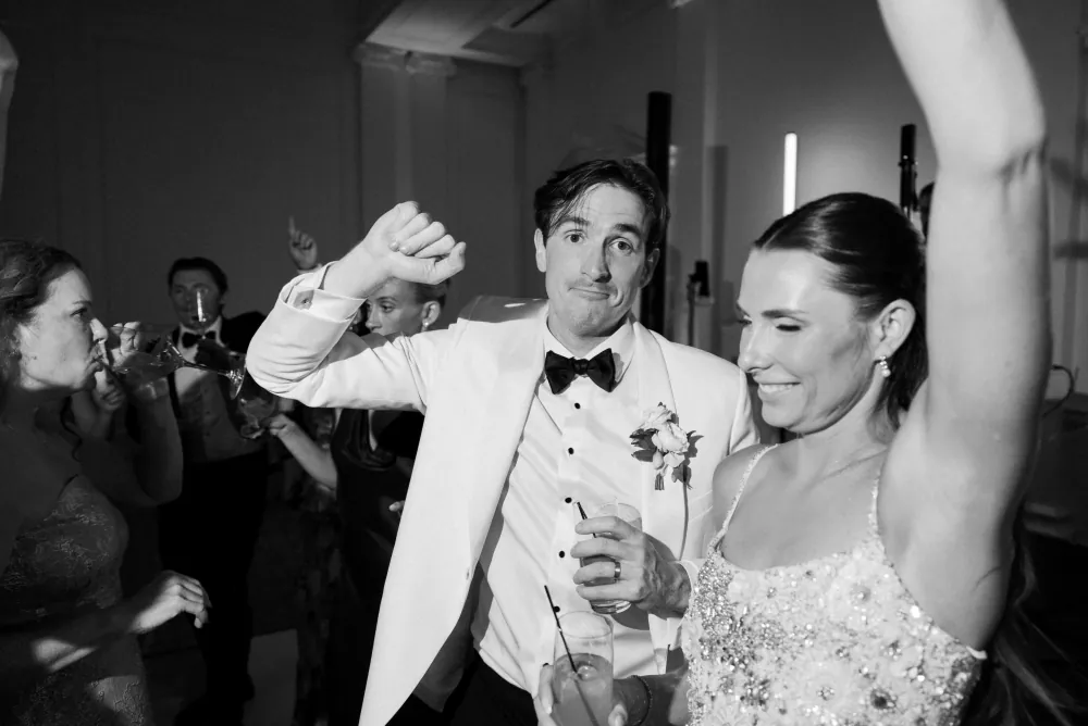 Bride and groom hanging on the gold-inlay checker dance floor in the Timuquana Country Club ballroom with arched windows behind