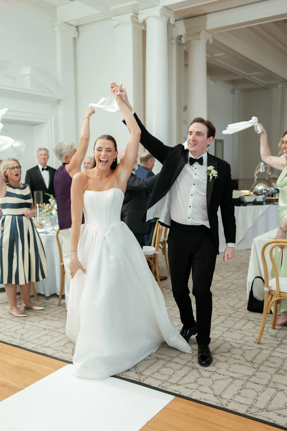Bride and groom reception entrance with arms raised and guests twirling napkins at Timuquana Country Club