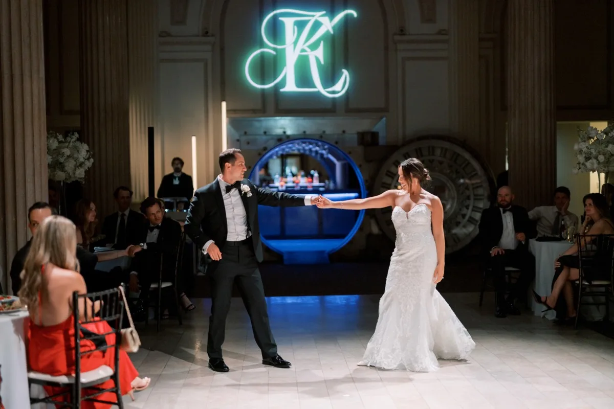 Bride and groom first dance under custom monogram projection at Treasury on the Plaza
