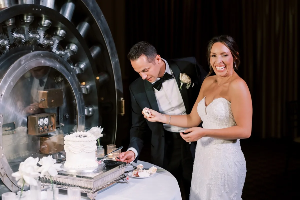 Bride and groom cut wedding cake at the historic bank vault at Treasury on the Plaza